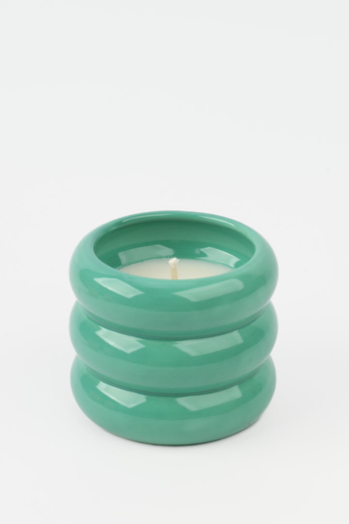 green glossy ceramic candle holder with rounded stacked shape and white wax inside
