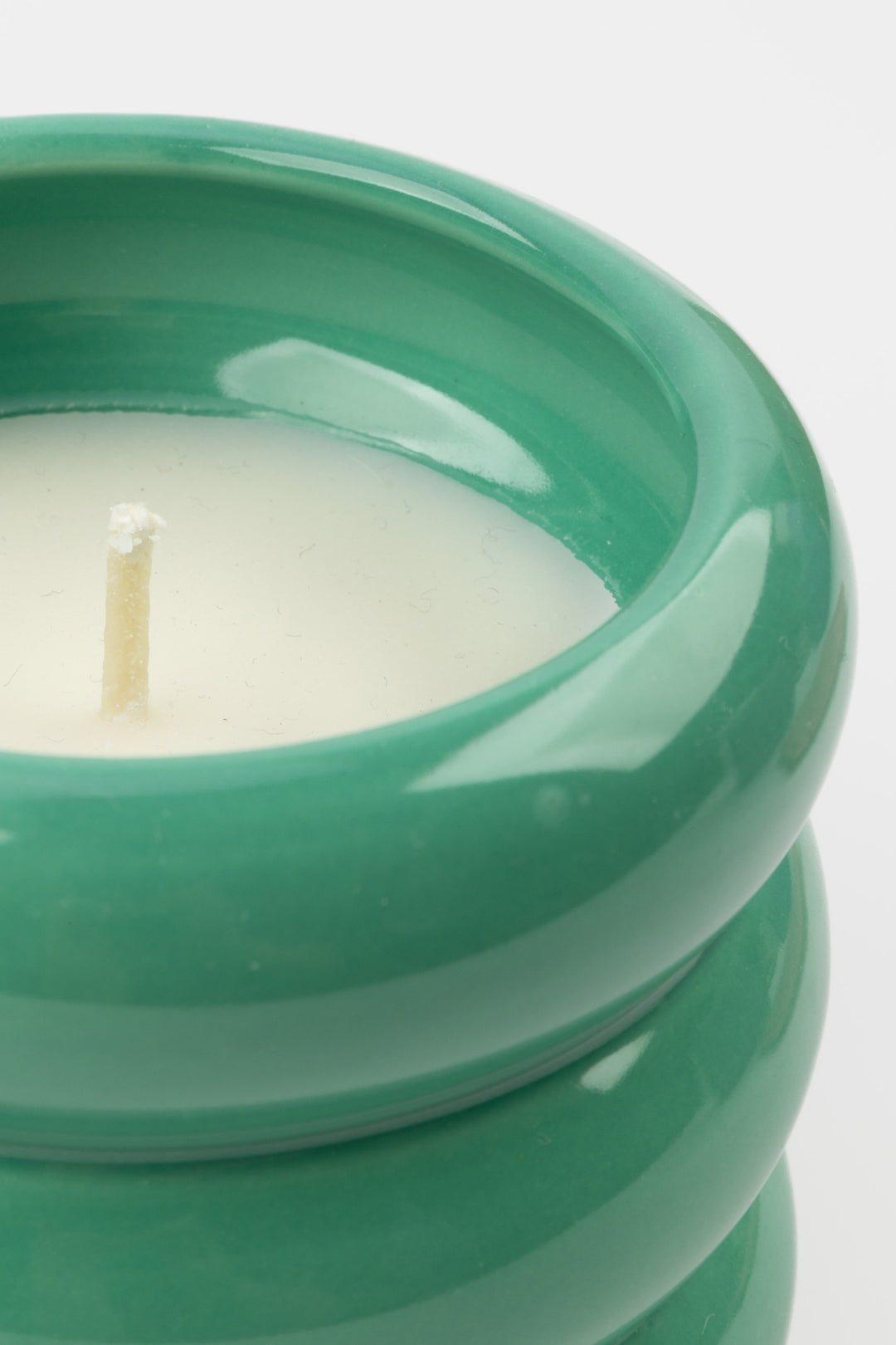 close-up of green ceramic candle showing glossy rim and white wax
