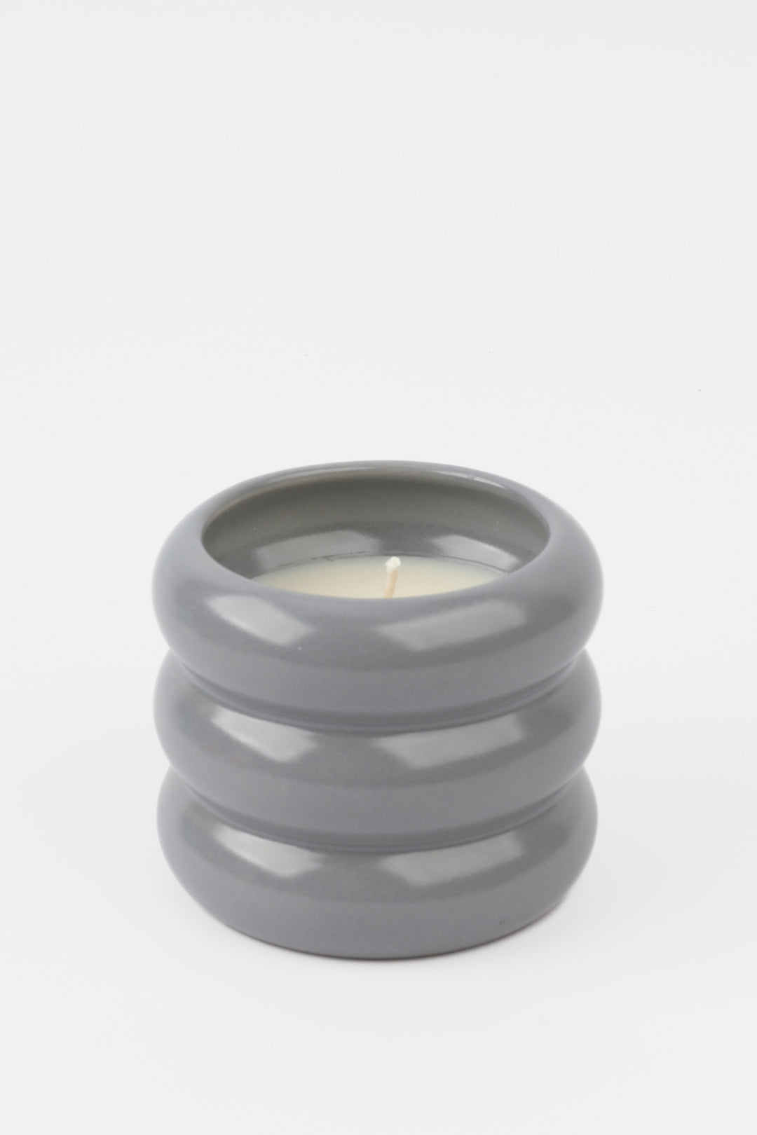 grey glossy ceramic candle holder with rounded stacked shape and white wax inside
