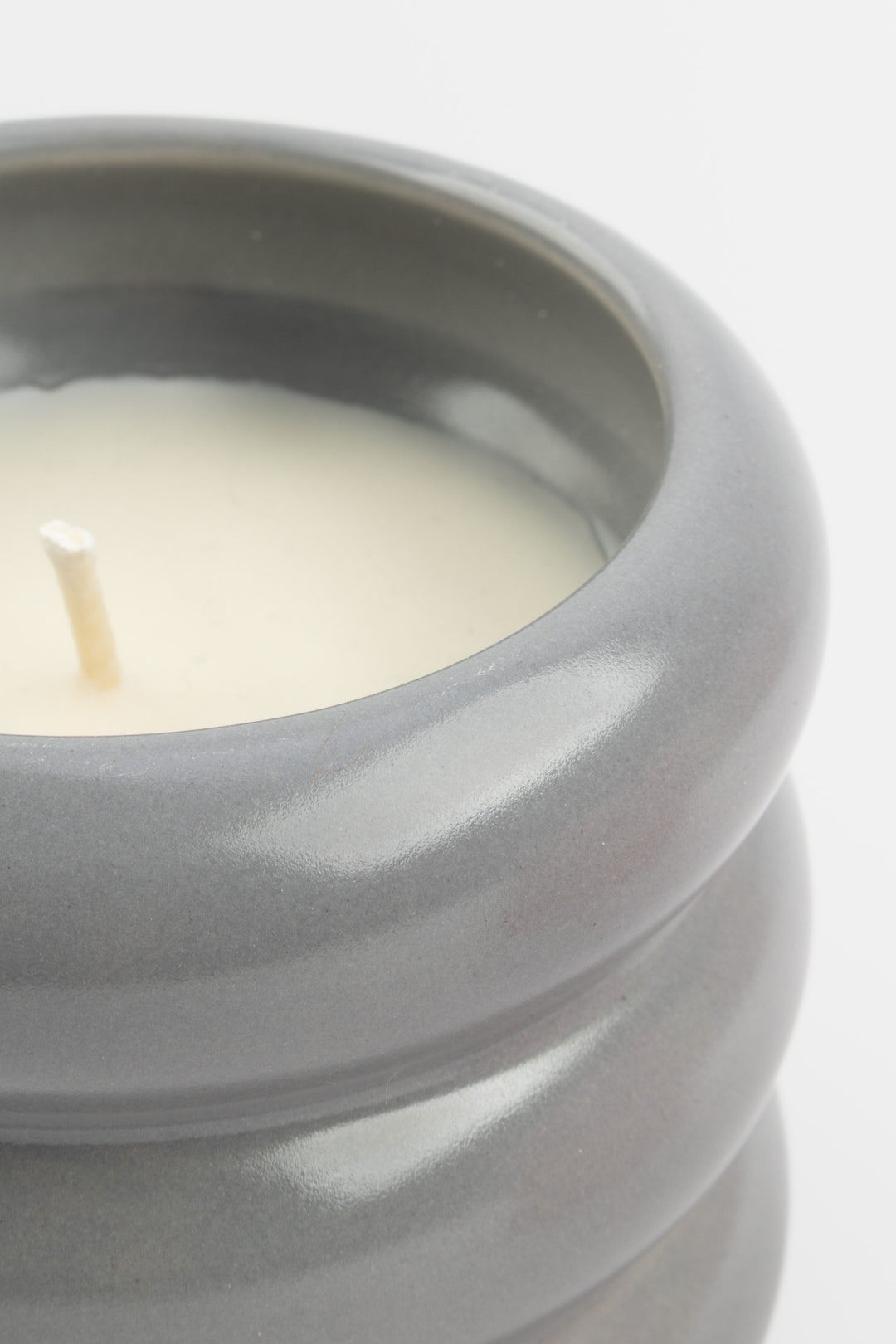 close-up of grey ceramic candle showing glossy rim and white wax
