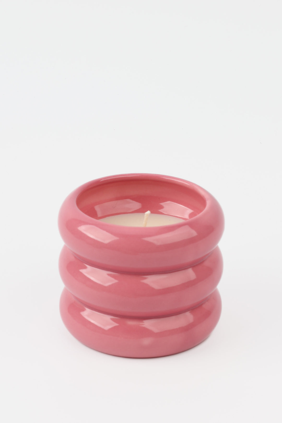 pink glossy ceramic candle holder with rounded stacked shape and white wax inside