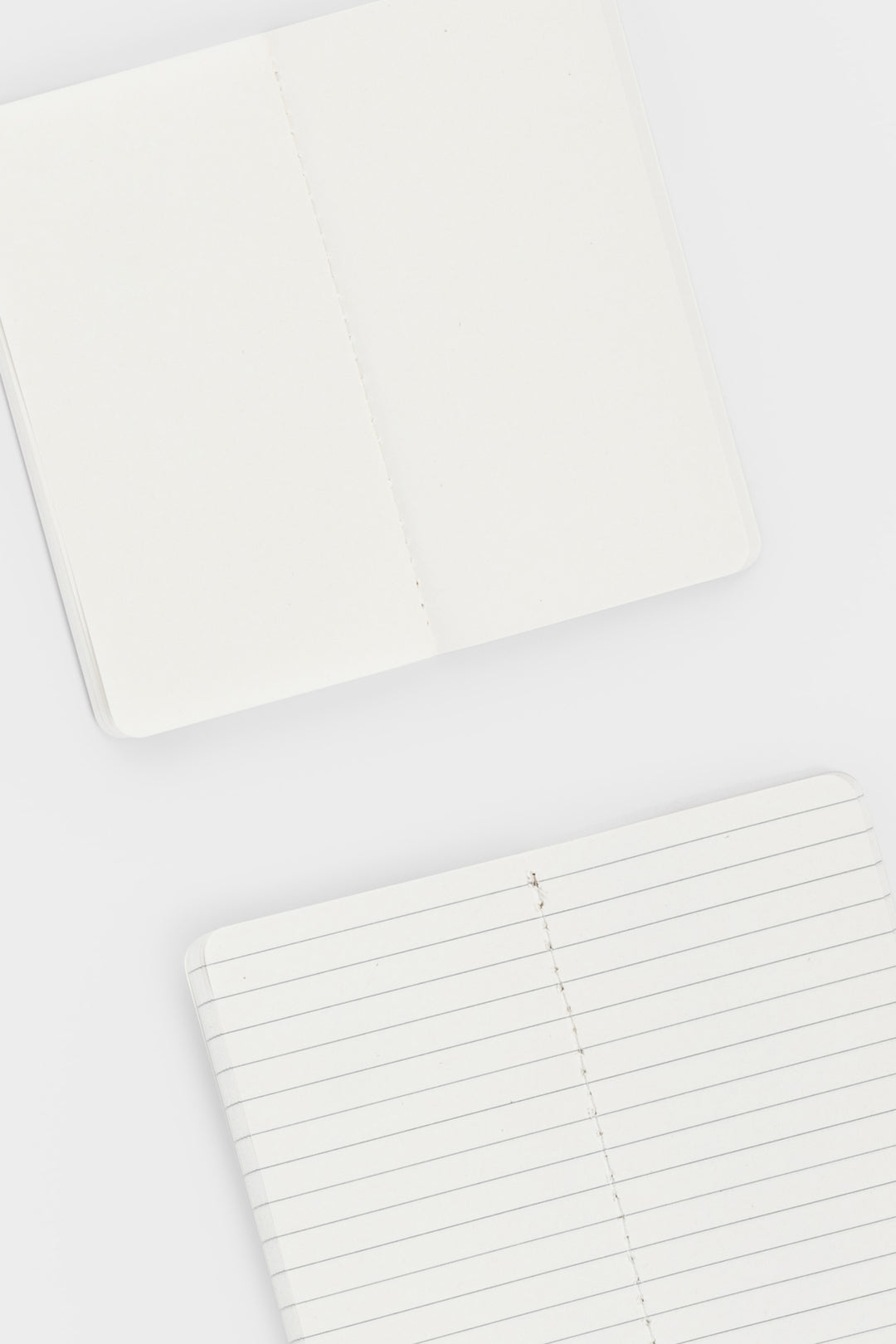 2 opened notebooks showing blank and lined pages and stitching