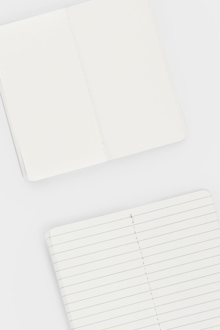 2 opened notebooks showing blank and lined pages and stitching