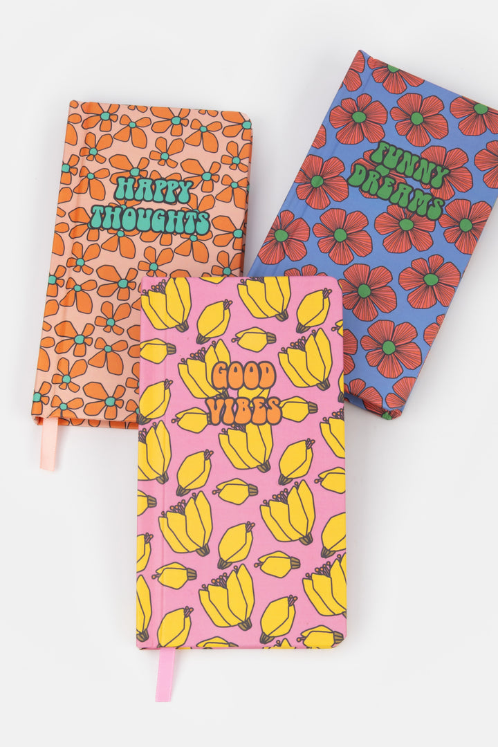 three patterned journals arranged flat with different retro prints and visible ribbon markers

