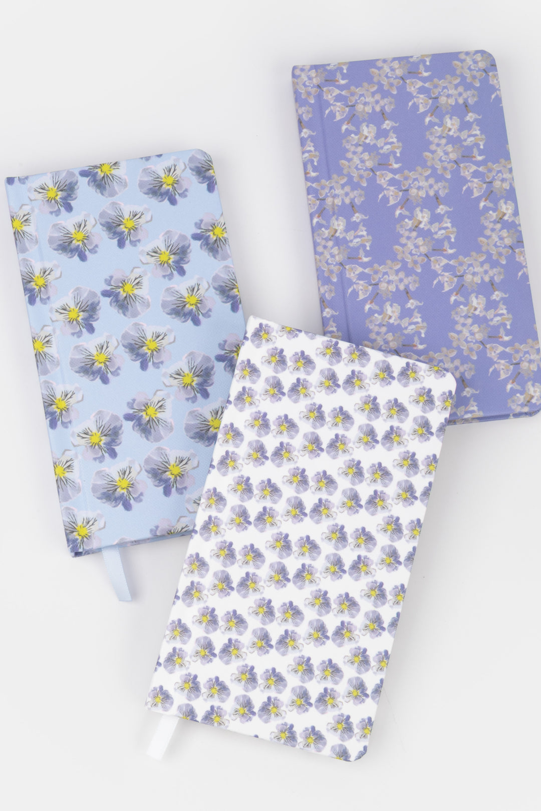 Three floral-patterned notebooks on a white background