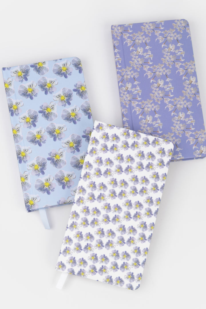 Three floral-patterned notebooks on a white background