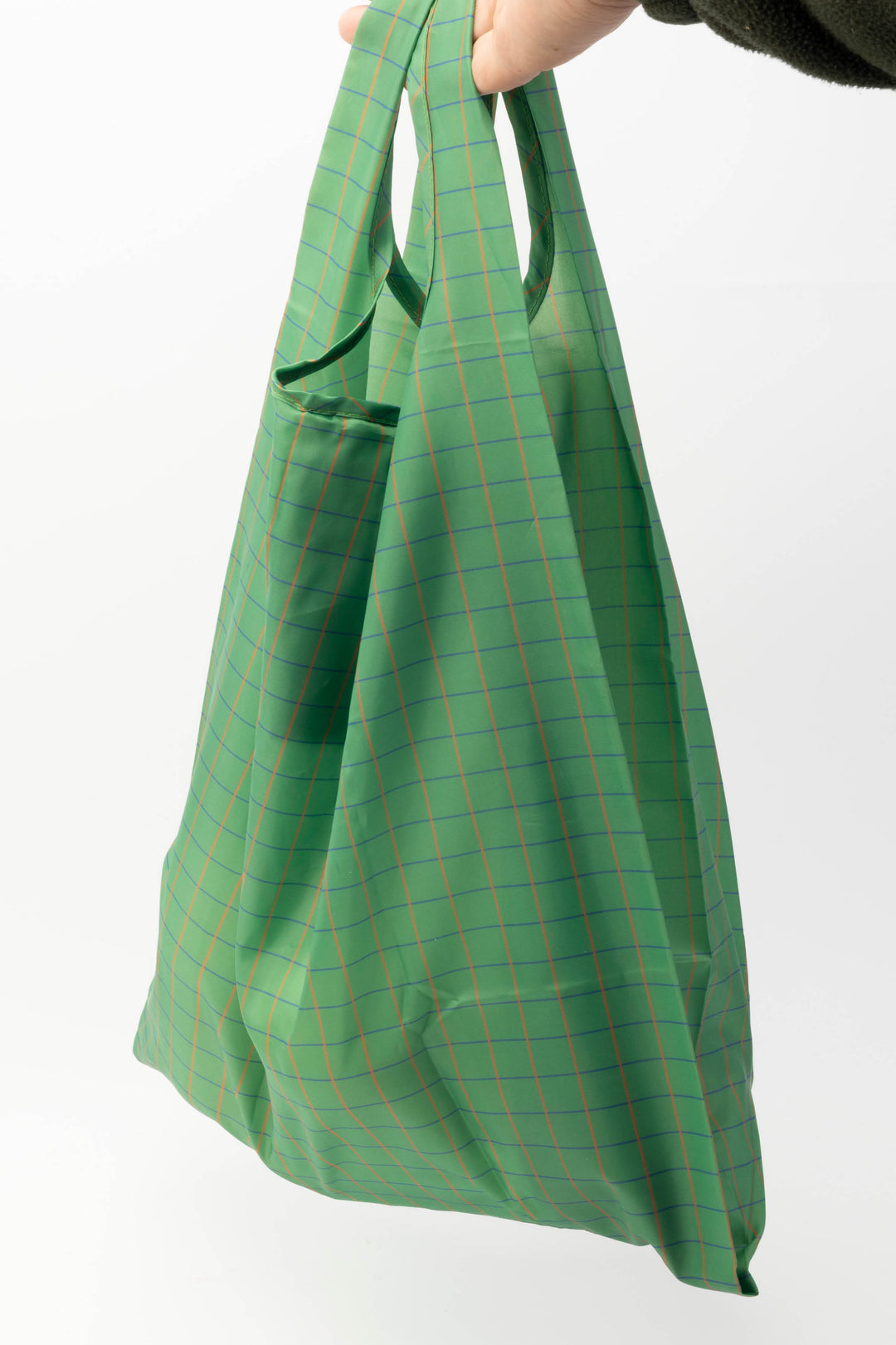 Green plaid large reusable bag held by a hand on a white background