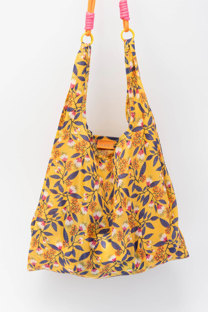 Yellow medium floral-patterned bag with pink handles on a white background