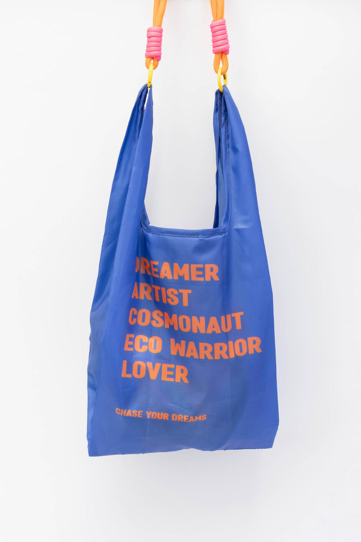 Blue small reusable bag with motivational text and colourful handles on a white background