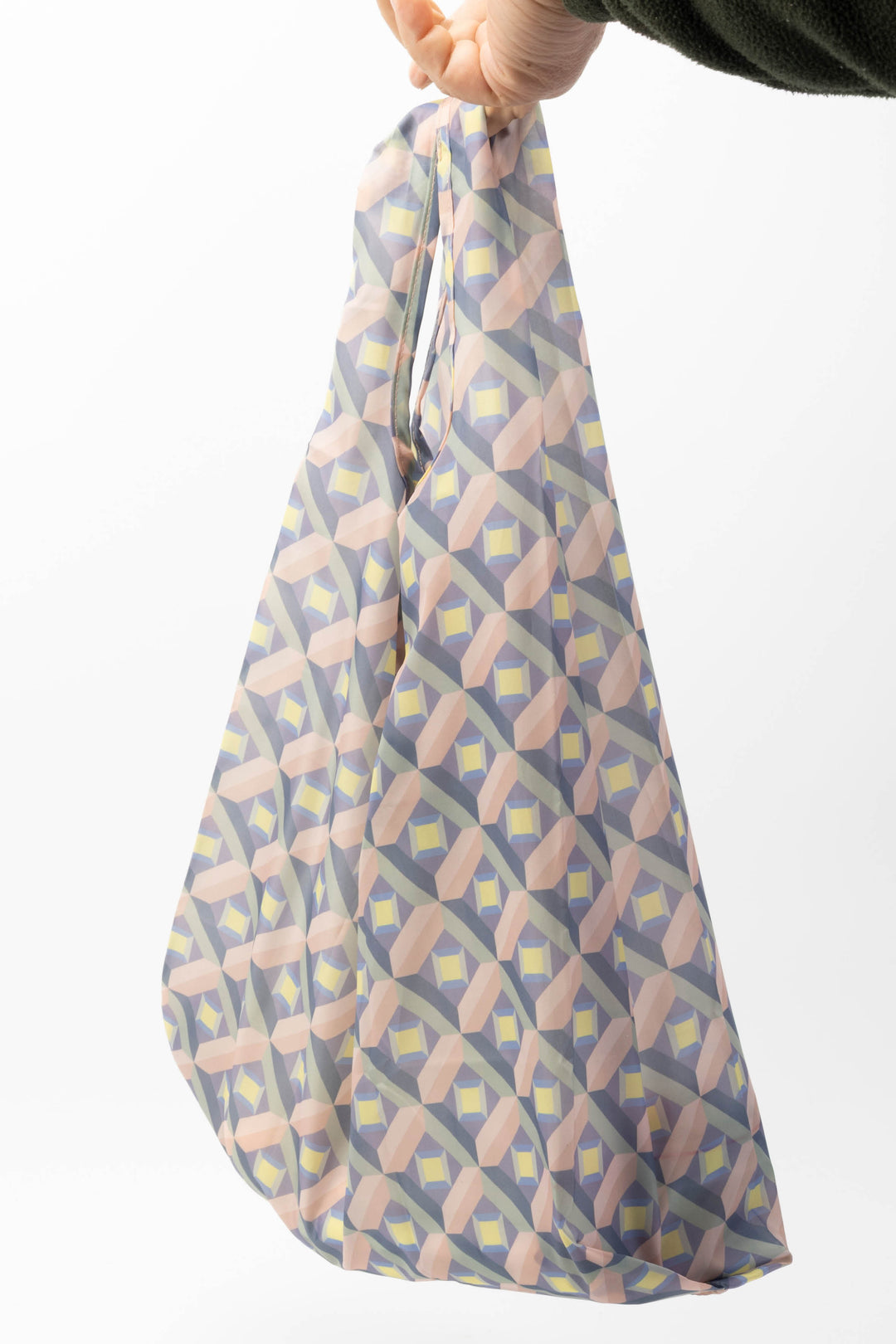 Patterned reusable shopping bag held by a hand on a white background