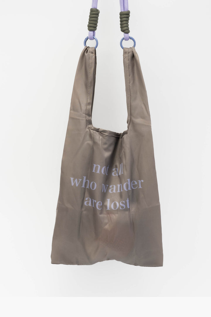 Brown reusable bag with text hanging against a white background