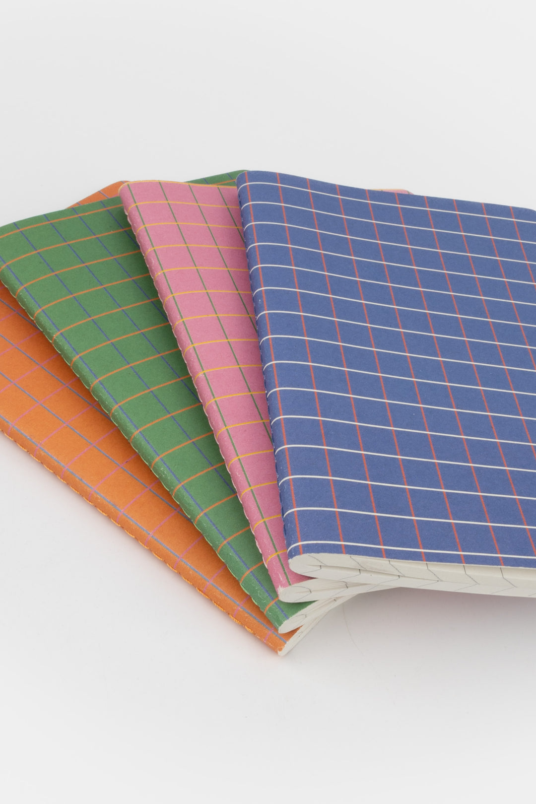 Four notebooks with colorful checkered covers on a white background
