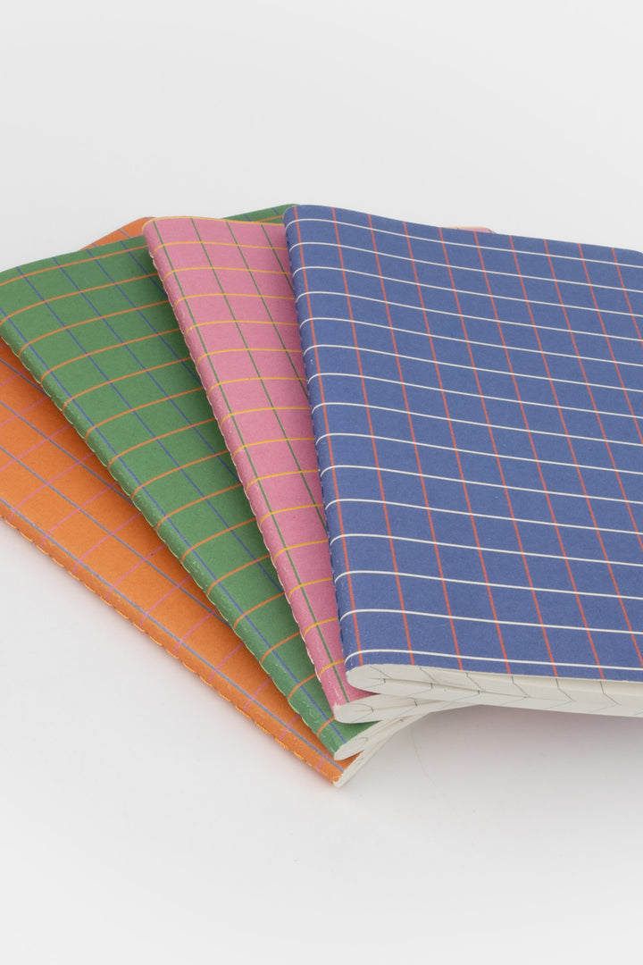 Four notebooks with colorful checkered covers on a white background