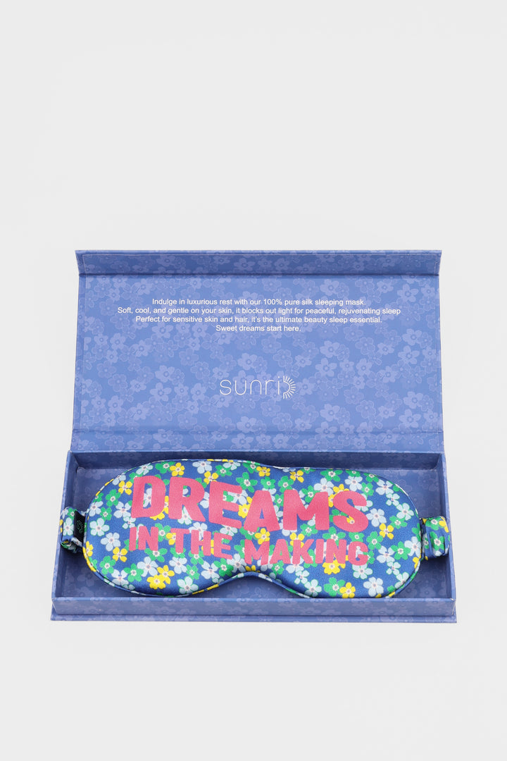 Floral sleep mask with 'Dreams in the Making' text in a blue floral-patterned box on a white background.