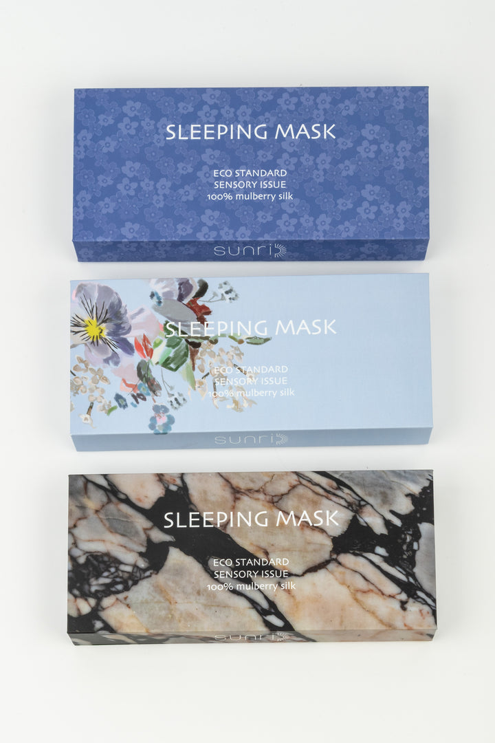 Three sleeping mask boxes with floral, marble, and blue designs on a white background.