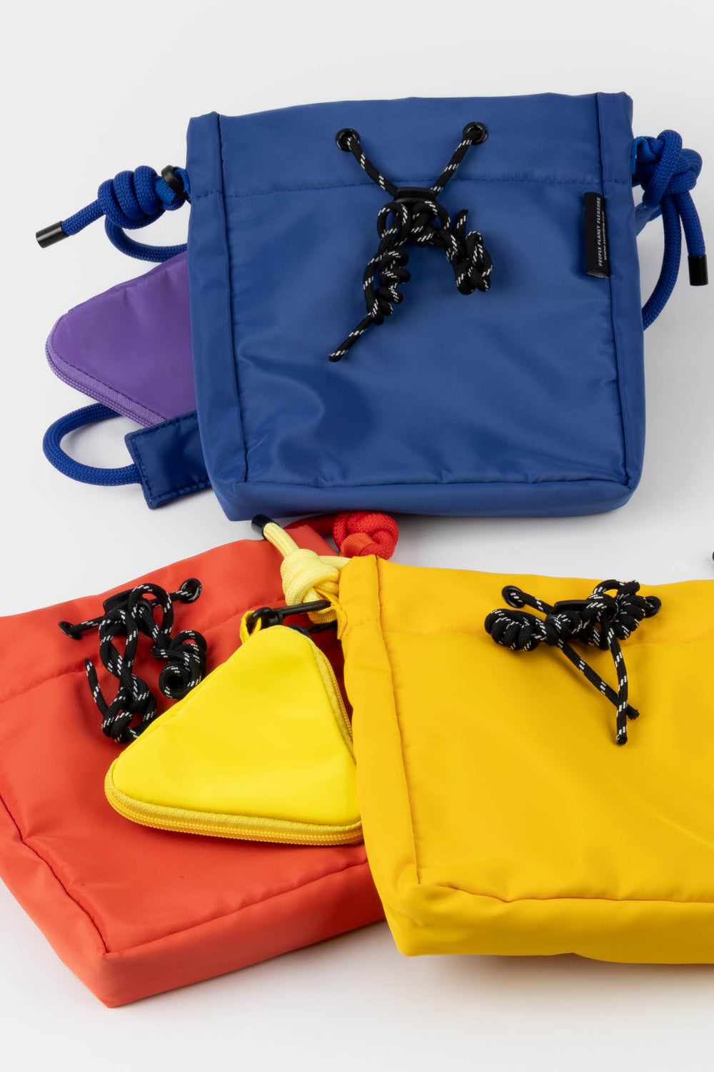 Four colorful drawstring bags in blue, yellow, red, and orange on a white background.