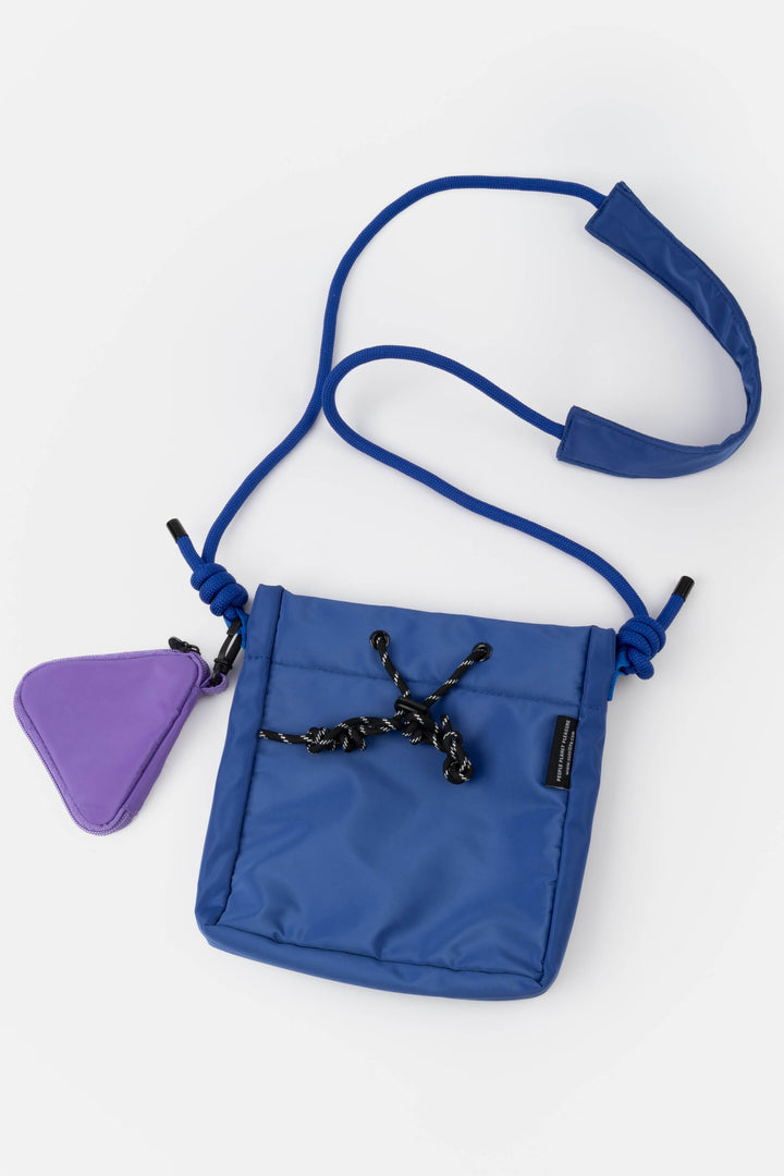 Blue crossbody bag with a purple triangle-shaped pouch on a white background