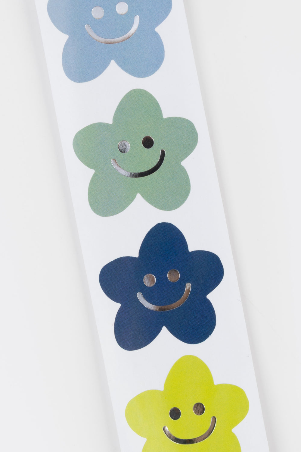 Close-up of a white surface with blue, green, yellow, and purple smiley face flowers stckers.