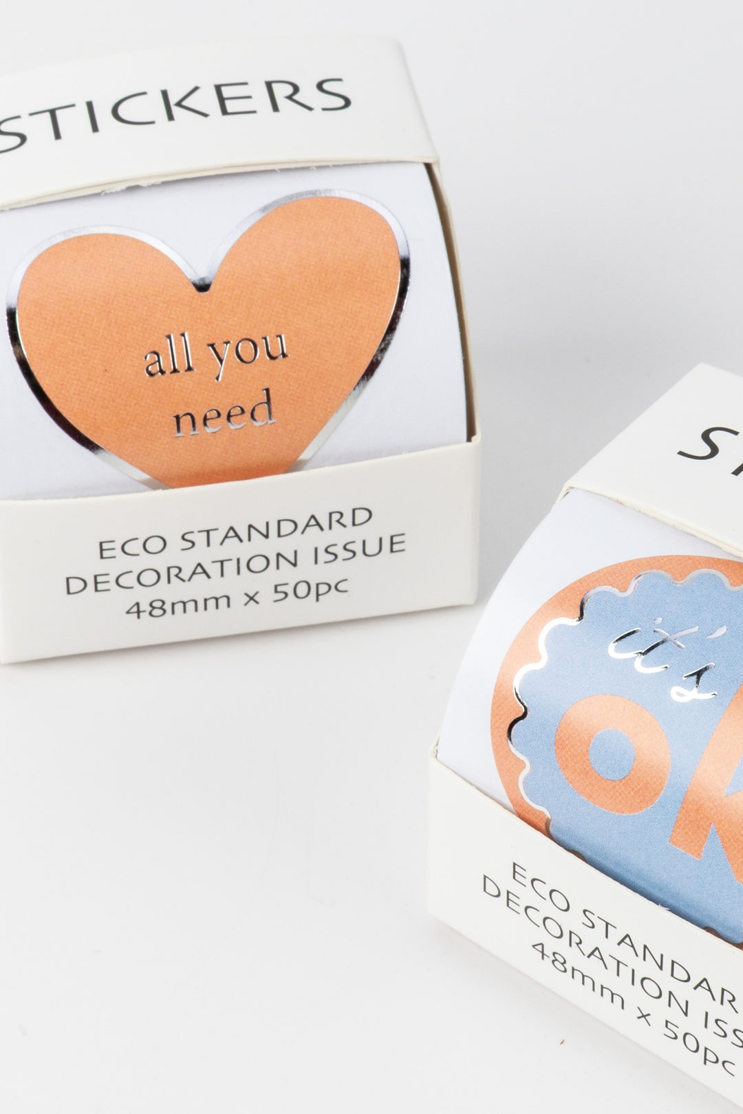 Two boxes of stickers with heart-shaped designs and text on a white background
