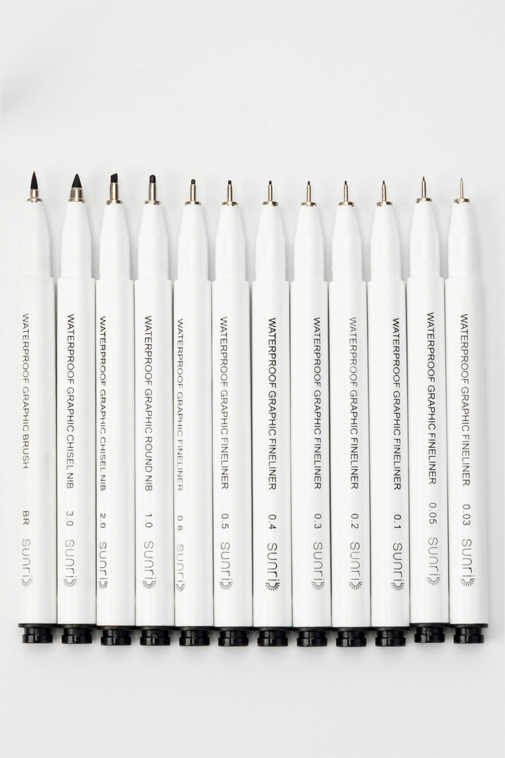 waterproof graphic pens with exposed tips showing brush tip, chisel nib and fine metal fineliner points
