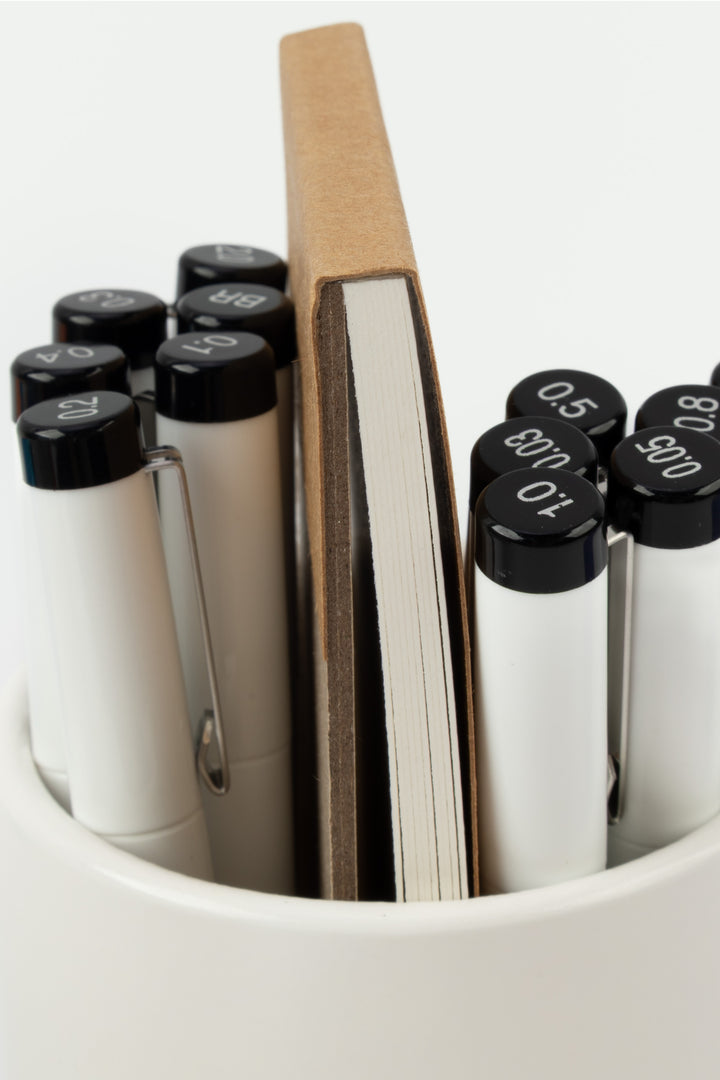 Set of markers with black caps in a container on a white background
