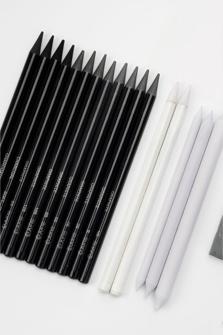 black woodless graphite sketching pencil set arranged diagonally with white blending stumps and eraser visible
