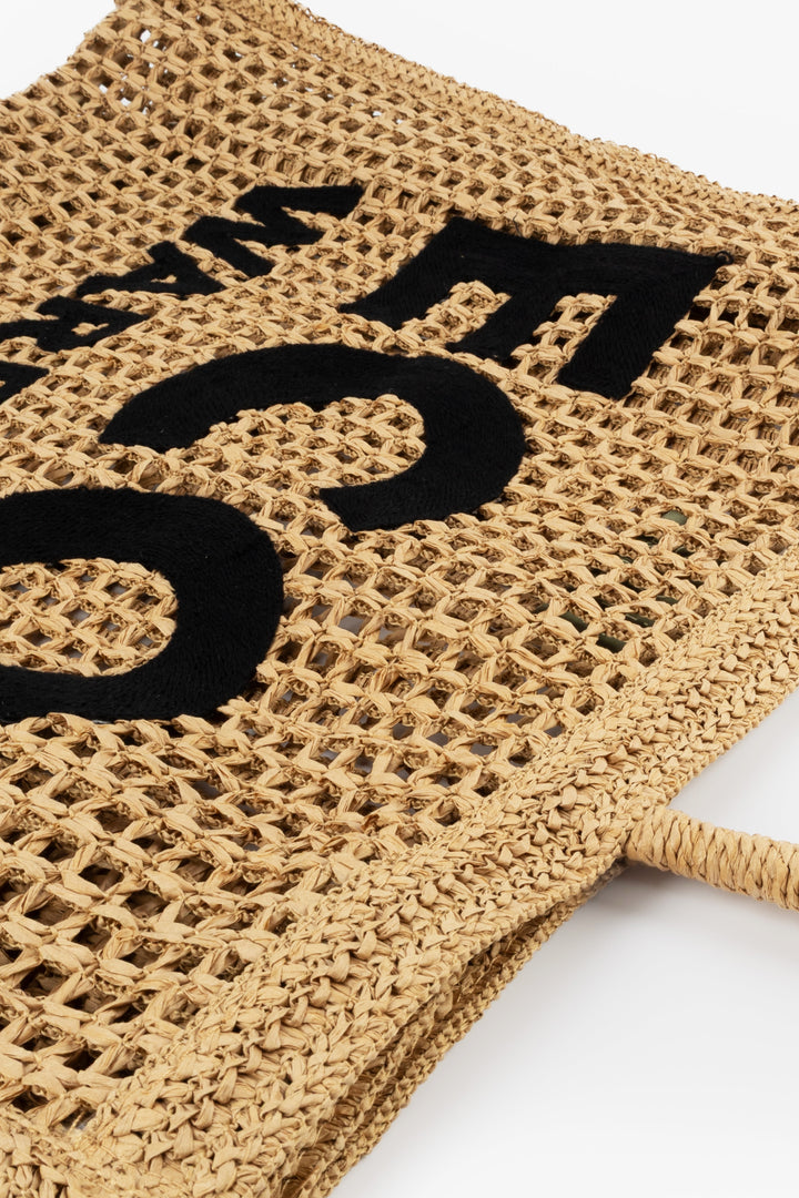 Close-up of a woven bag with black text on a white background