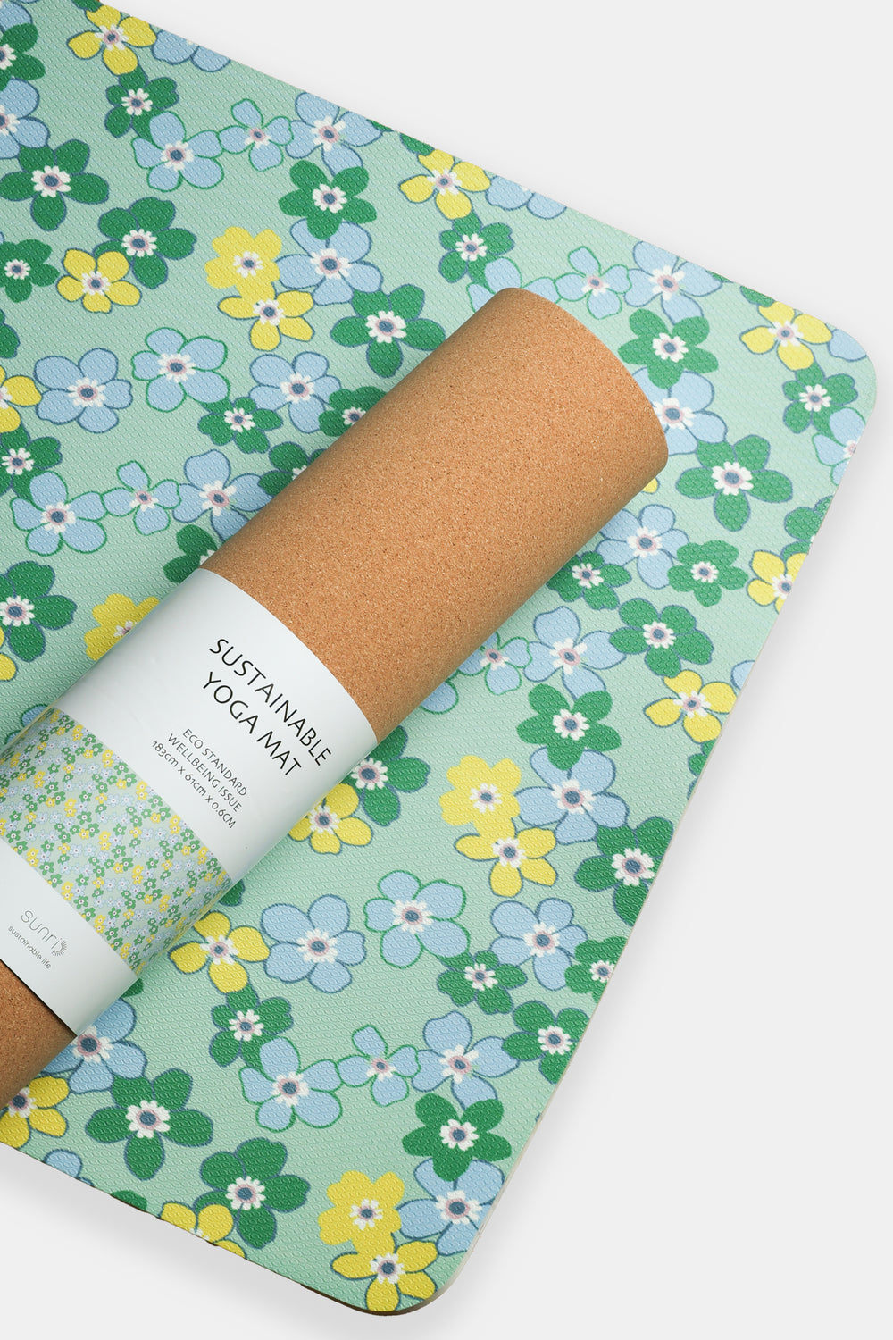 yoga mat with daisy floral pattern partially rolled with cork backing and paper belly band
