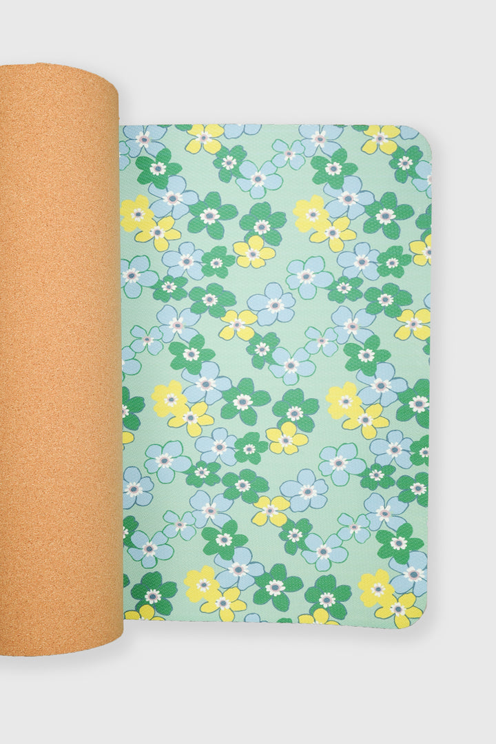 yoga mat half unrolled showing daisy floral surface with cork backing visible
